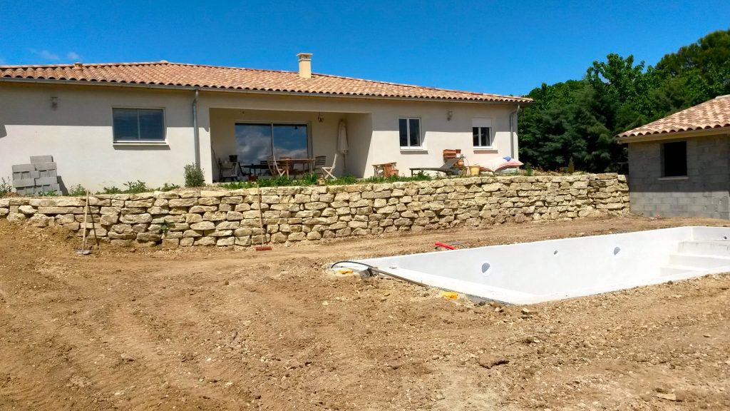 Enrochement pour muret en pierre dans jardin de maison individuelle Enrochement pour muret en pierre dans jardin de maison individuelle