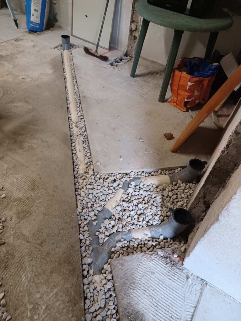 Mise en place des tuyaux PVC dans du gravier dans la dalle béton de la maison