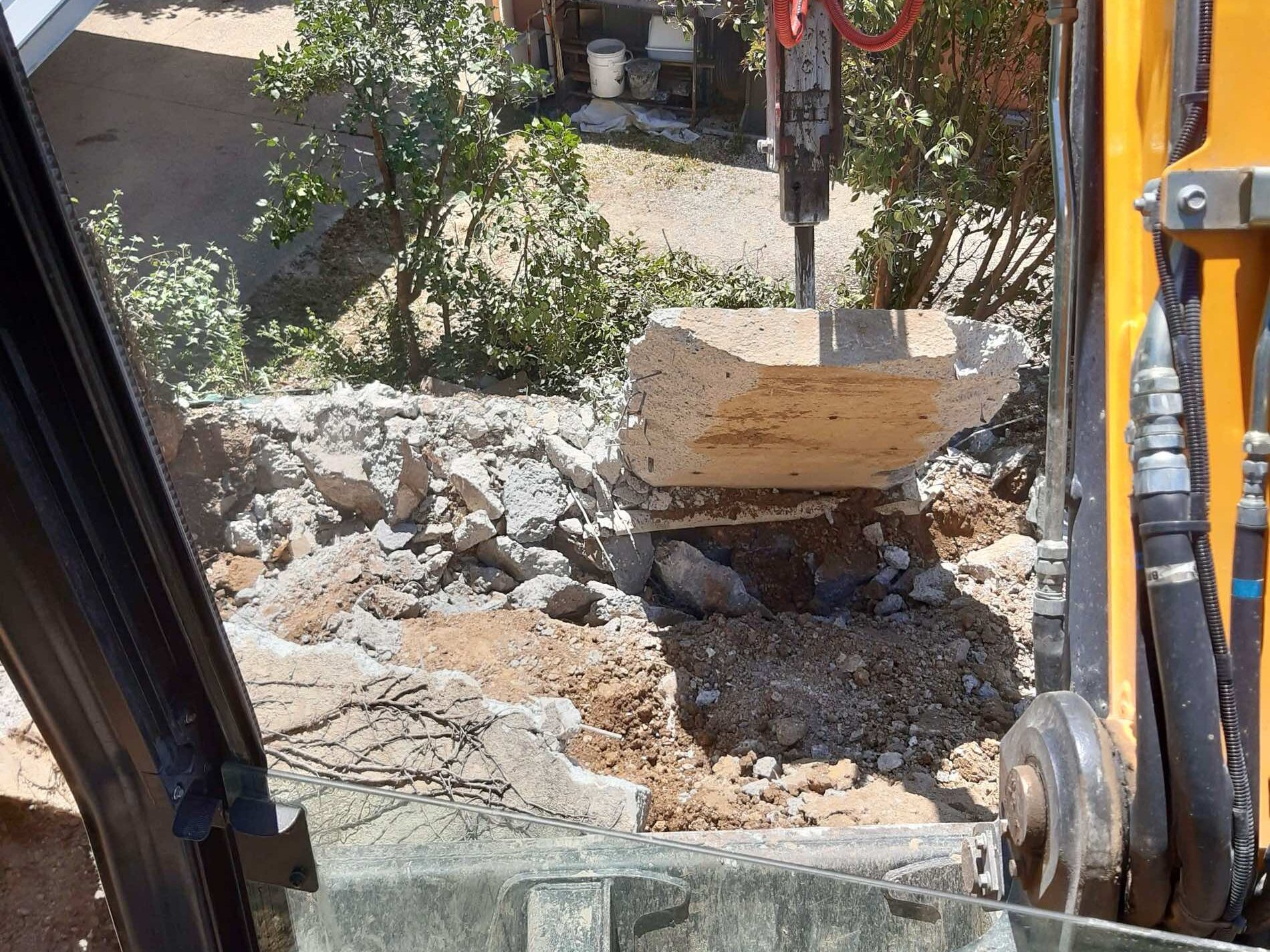 Chantier de démolition et déblaiement d'un mur autour d'une piscine.