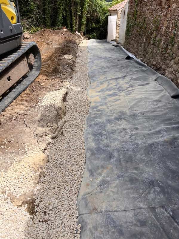 Gravier drainant étalé le long de la géomembrane, mini-pelle sur le côté
