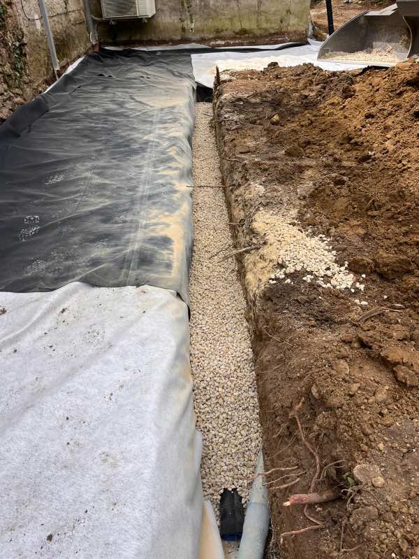 Tranchée de drainage remplie de gravier blanc au-dessus du drain